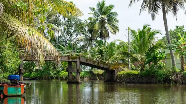 Quiet inland backwater canal in Kerala with traditional homes and reflections